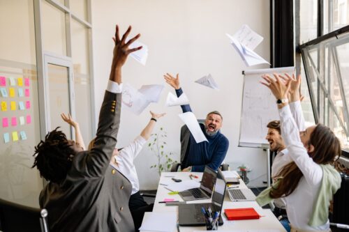 a group of people at work throwing papers