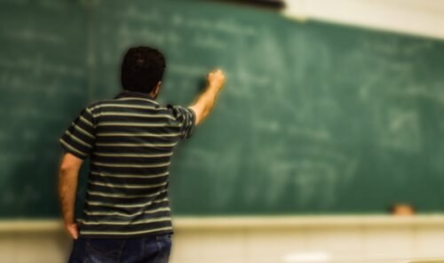 man in black and white polo shirt beside writing board