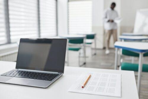 a laptop on the table with paper and pencil on the side