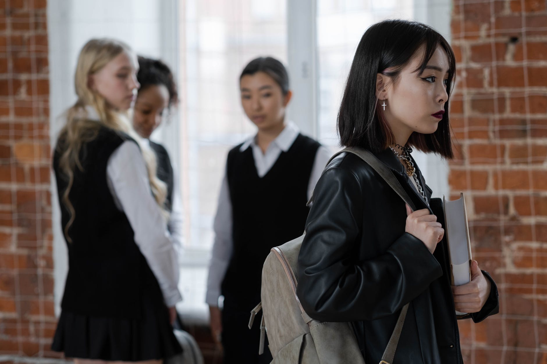 shallow focus of a girl in black leather jacket holding a book
