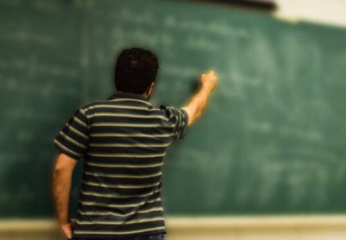 man in black and white polo shirt beside writing board