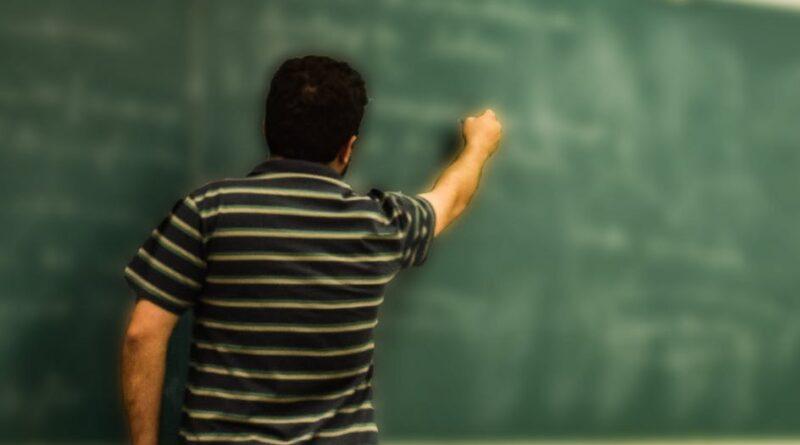 man in black and white polo shirt beside writing board